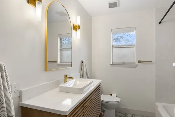 an empty room with wooden floor chandelier fan and windows