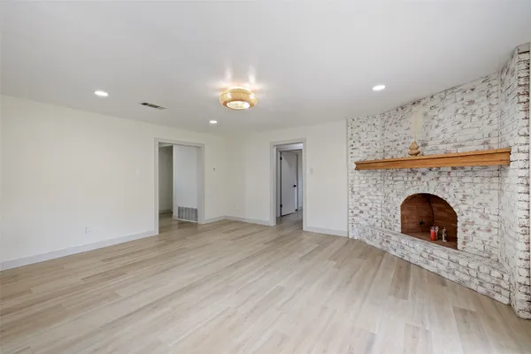an empty room with fireplace and wooden floor