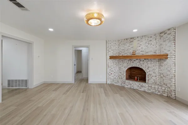 an empty room with wooden floor and a fireplace