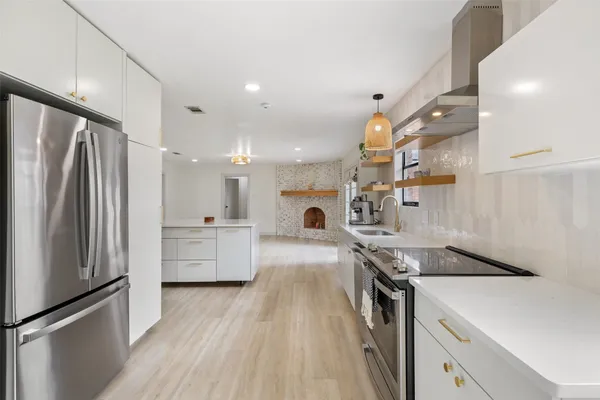 a kitchen with stainless steel appliances a stove a sink and a refrigerator with wooden floor