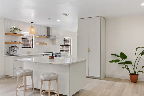 a kitchen with white cabinets and wooden floor