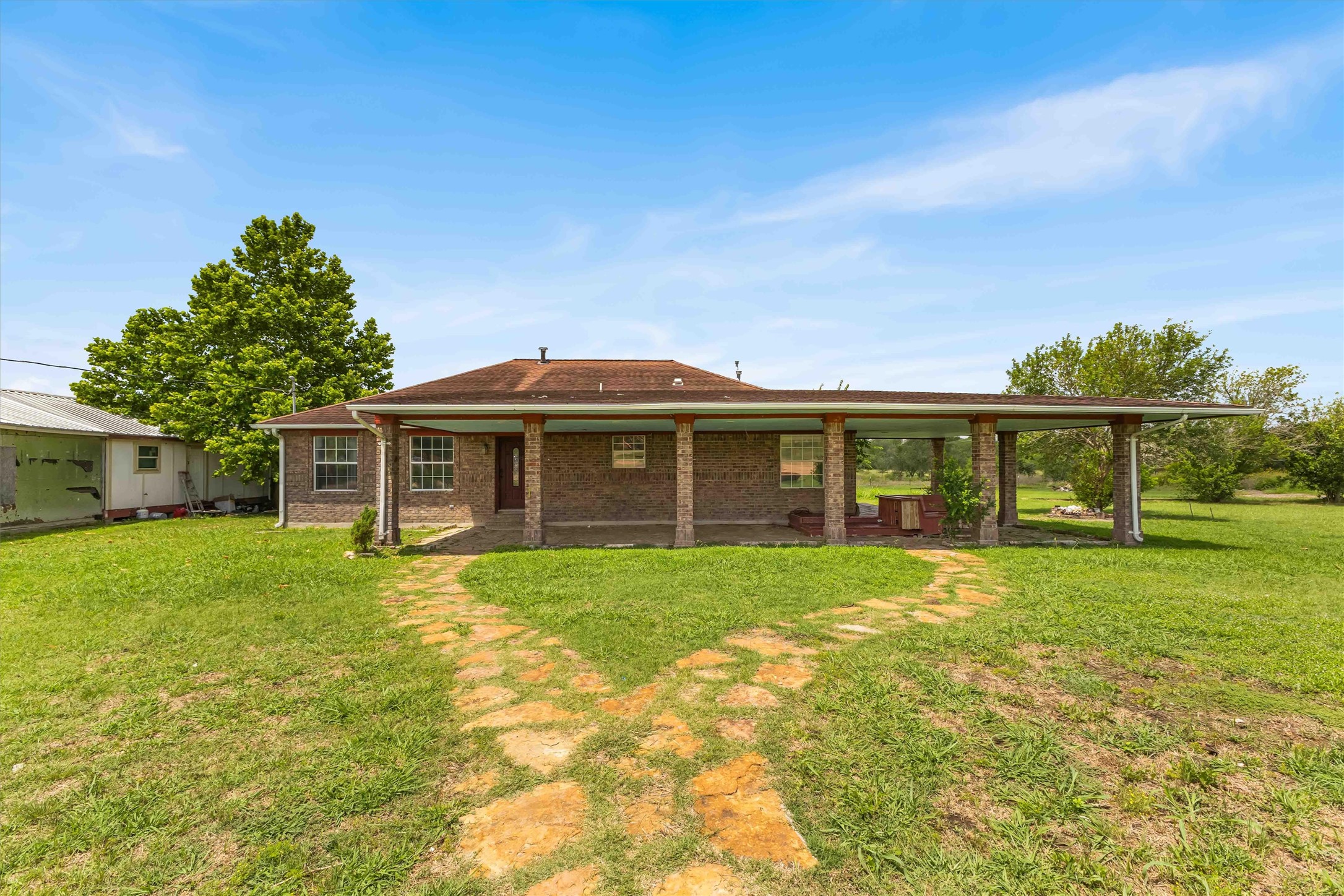 12212 Ballerstedt Road Elgin, TX 78621 - Photo 2 of 39 Back of property featuring a lawn, brick siding, and a patio area