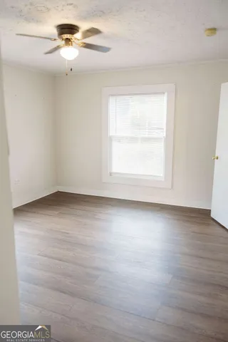 an empty room with wooden floor chandelier fan and windows