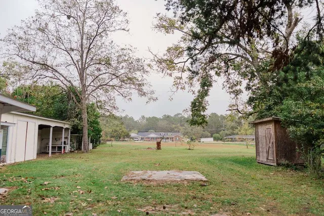 a view of a house with backyard and trees