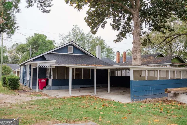 a view of a house with a yard and a large tree