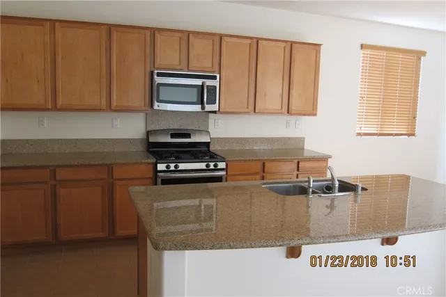 a kitchen with stainless steel appliances granite countertop a sink a microwave cabinets and a stove top oven