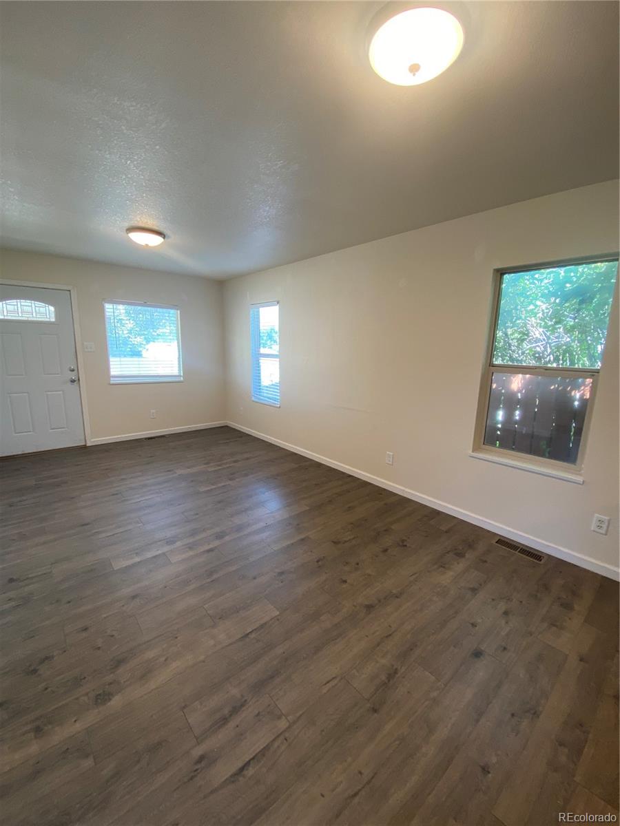 613 Lake Street Rangely, CO 81648 - Photo 3 of 12 an empty room with wooden floor and windows