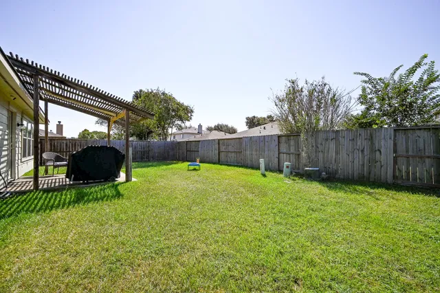 a view of a backyard with table and chairs a barbeque and wooden fence