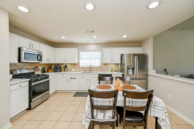 a kitchen with a dining table chairs and refrigerator