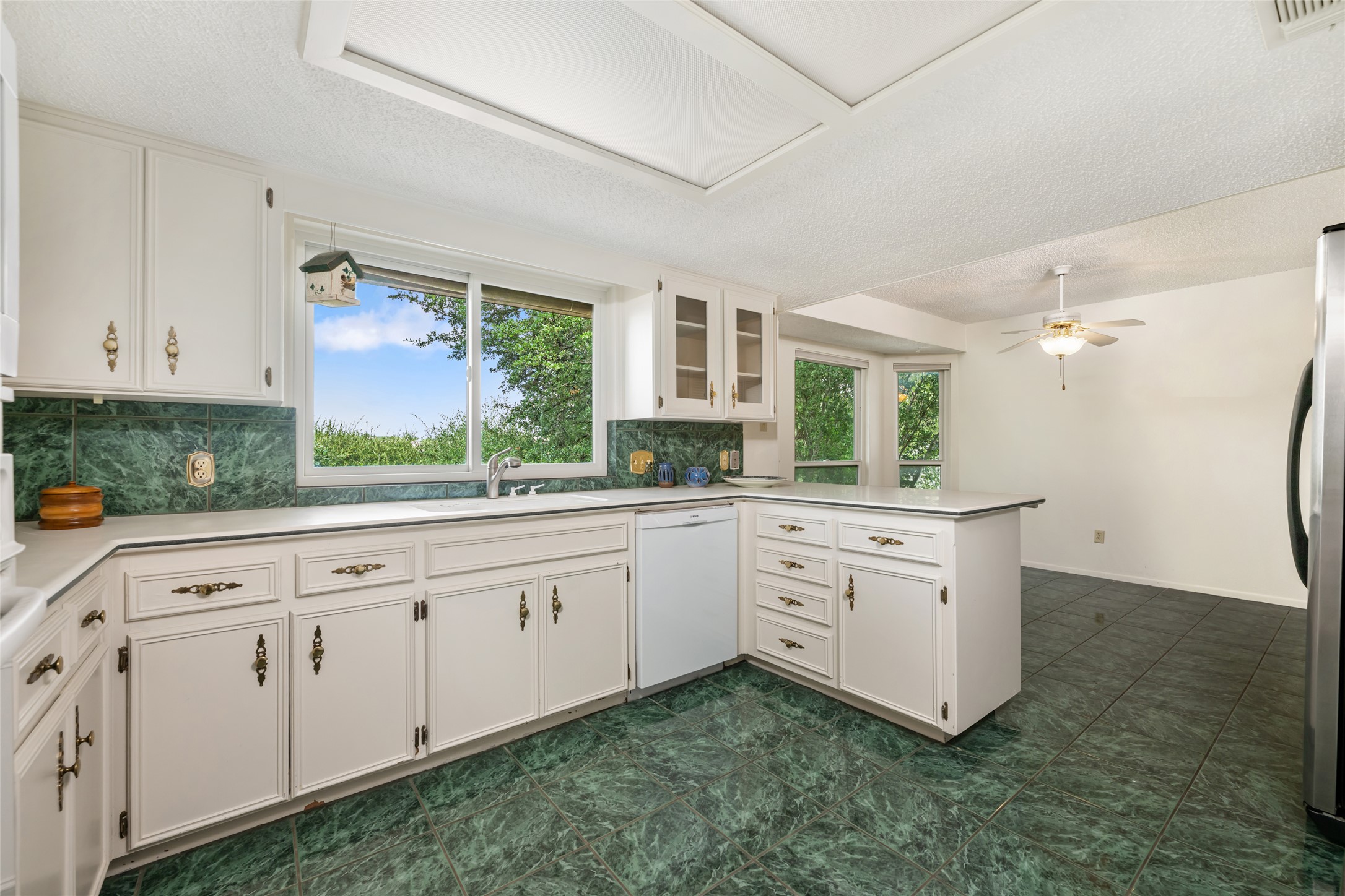 5319 Musket Ridge Austin, TX 78759 - Photo 12 of 39 A classic kitchen with white cabinetry and a striking green tile backsplash and flooring.