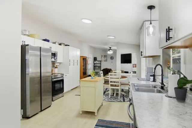 a kitchen with stainless steel appliances kitchen island granite countertop a refrigerator a stove a microwave oven a sink with a dining table and chairs