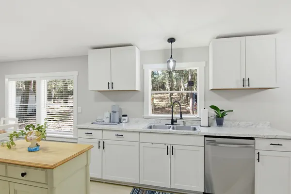a kitchen with stainless steel appliances white cabinets a sink a window and white appliances