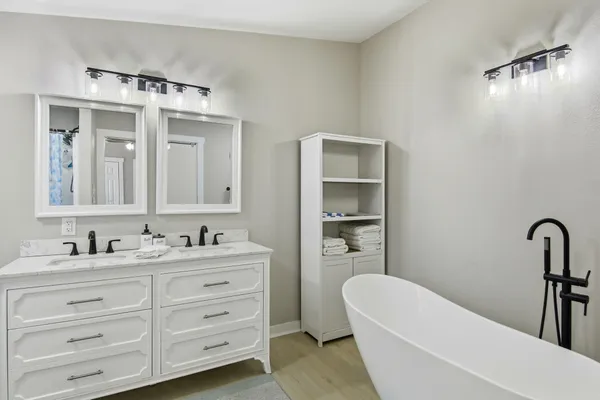 a bathroom with a double vanity sink mirror and bathtub