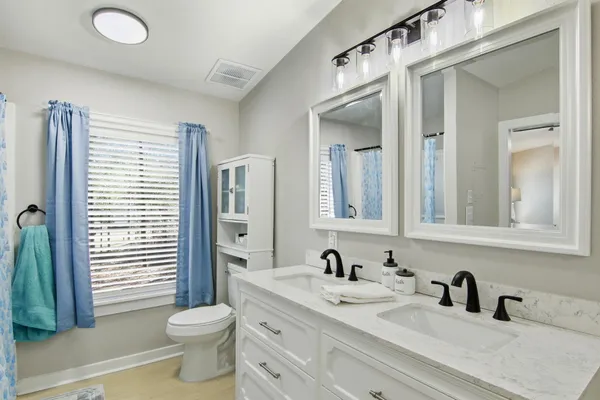 a bathroom with a granite countertop sink mirror vanity and toilet