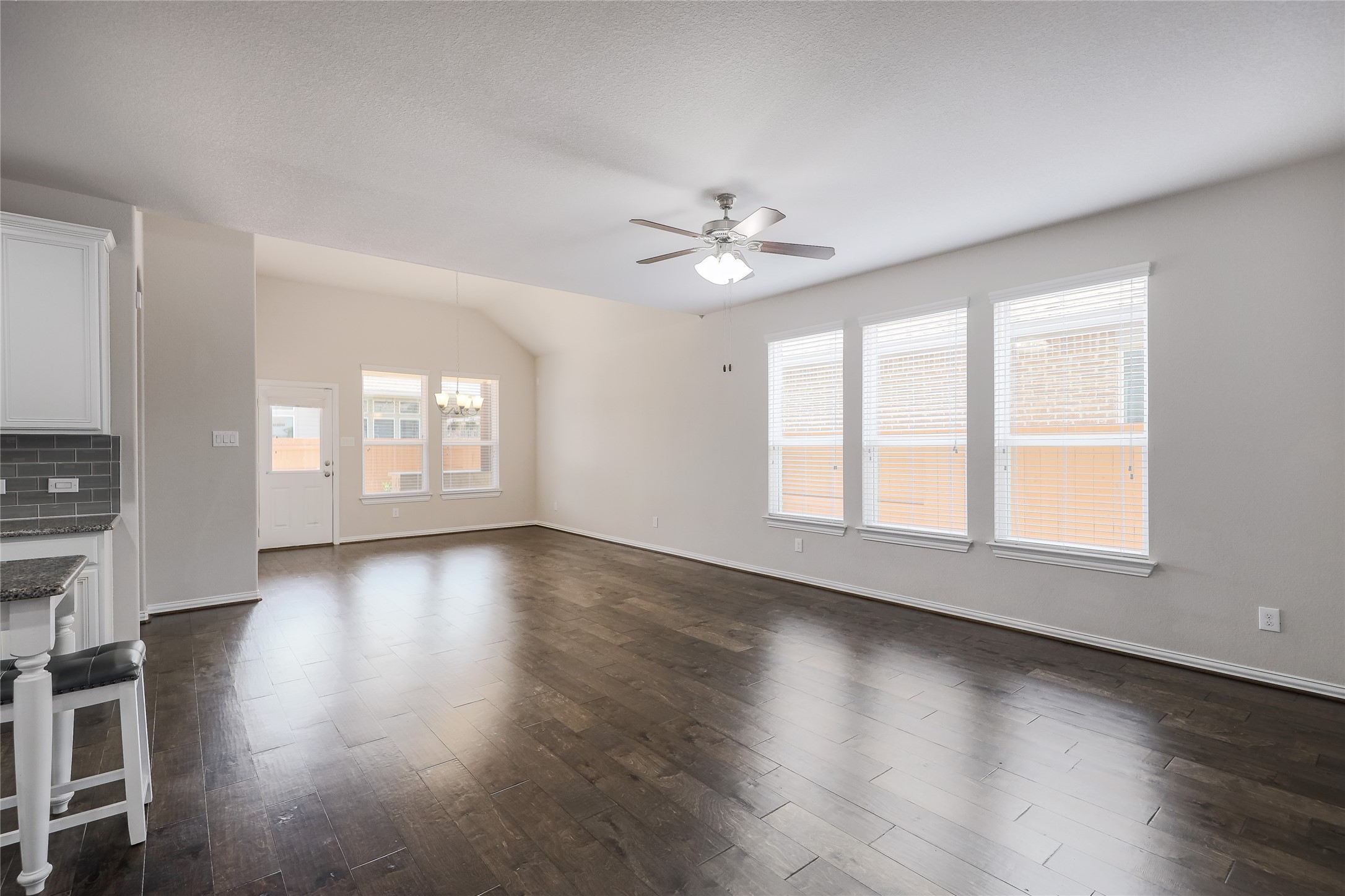 205 Penna Lane Georgetown, TX 78628 - Photo 4 of 32 Rich hardwood flooring stretches across this naturally illuminated living space, crowned by vaulted ceilings and a modern ceiling fan.