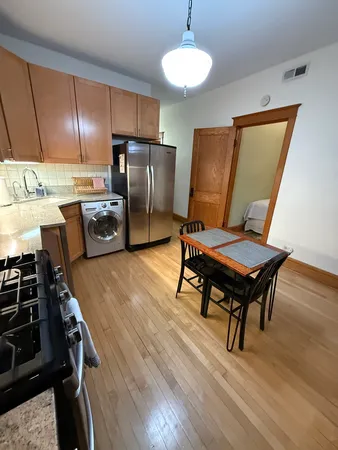 a kitchen with stainless steel appliances wooden floor and a stove top oven