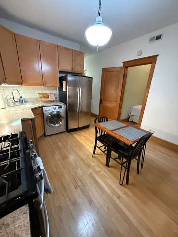 a kitchen with stainless steel appliances wooden floor and a stove top oven
