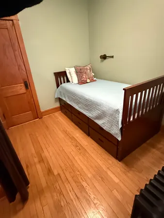 a bedroom with a bed and wooden floor
