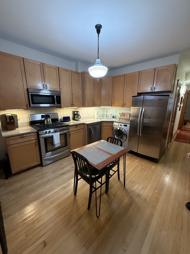 2134 North Damen Avenue, Unit 2 Chicago, IL 60647 - Photo 10 of 22 a kitchen with stainless steel appliances granite countertop a stove a refrigerator a kitchen island a sink dishwasher a dining table and chairs with wooden floor