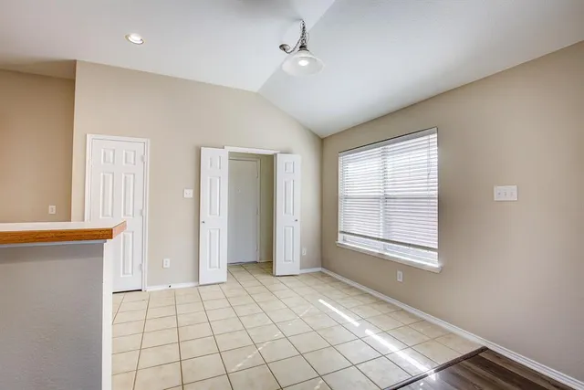a view of an empty room with window and chandelier fan