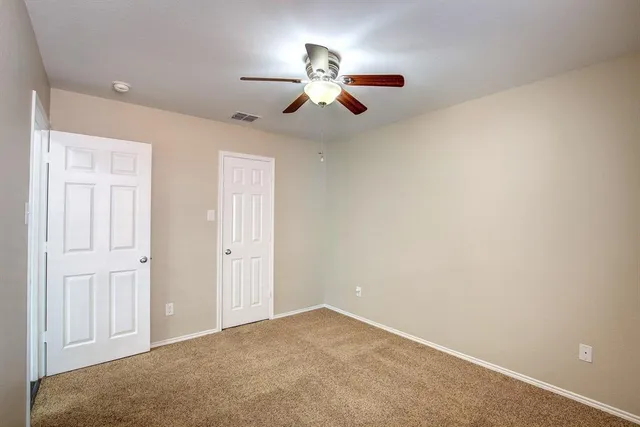 a view of an empty room and chandelier fan