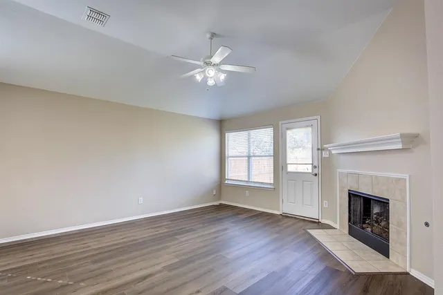 a view of empty room with wooden floor fireplace and fan