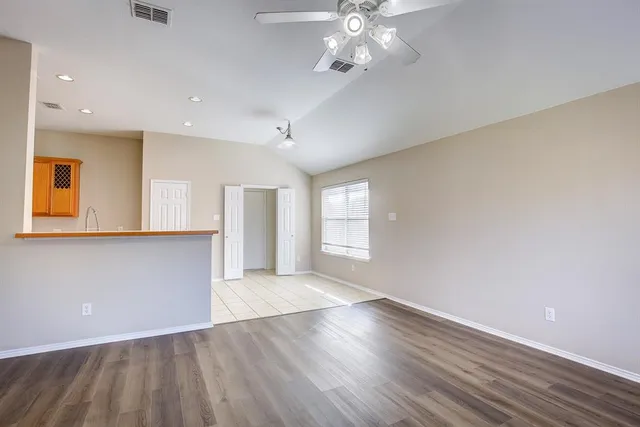an empty room with wooden floor and windows