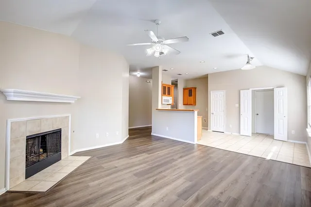 a view of an empty room with window and wooden floor