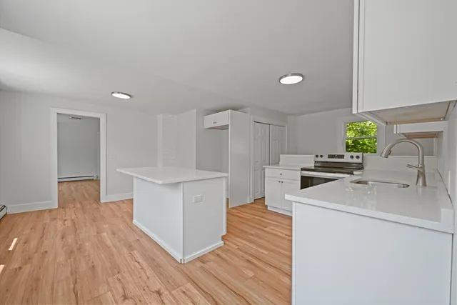 a kitchen with wooden floor sink and white appliances