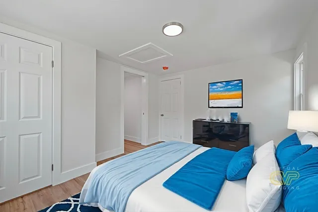 a bedroom with a bed and dresser with wooden floor