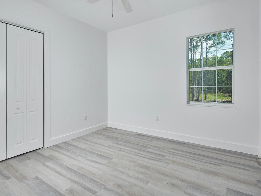 3677 Oil Well Road Naples, FL 34120 - Photo 16 of 28 an empty room with wooden floor and windows