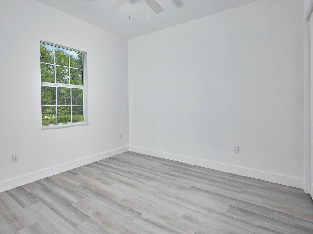 3677 Oil Well Road Naples, FL 34120 - Photo 18 of 28 an empty room with wooden floor and windows