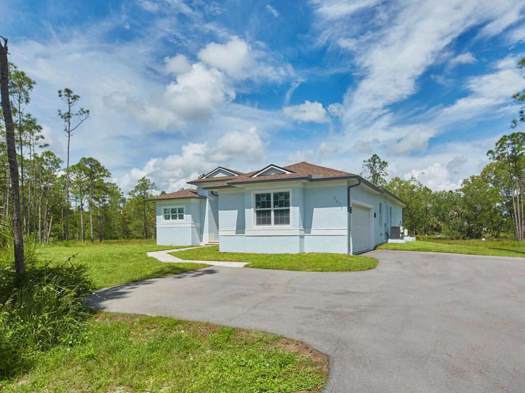 3677 Oil Well Road Naples, FL 34120 - Photo 22 of 28 a front view of a house with a yard and trees