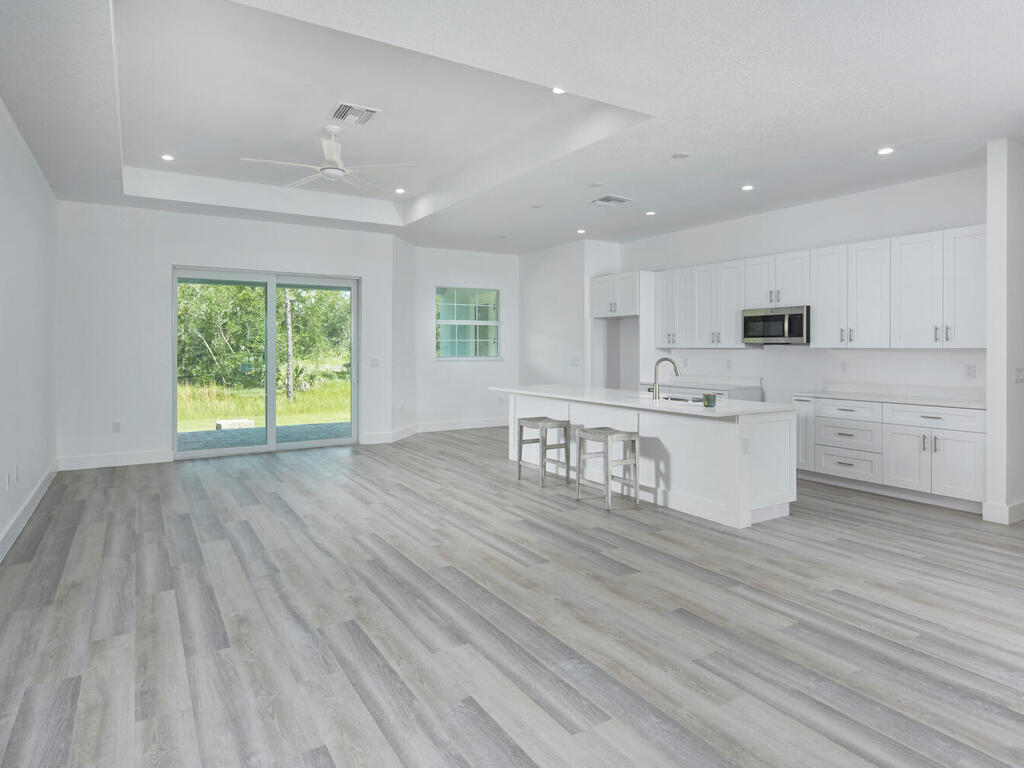 3677 Oil Well Road Naples, FL 34120 - Photo 4 of 28 a kitchen with stainless steel appliances granite countertop a stove a sink and white cabinets with wooden floor