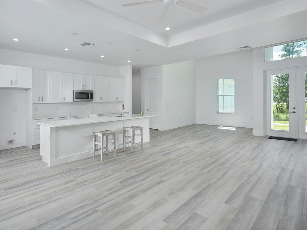 3677 Oil Well Road Naples, FL 34120 - Photo 28 of 28 a large white kitchen with wooden floors and white stainless steel appliances