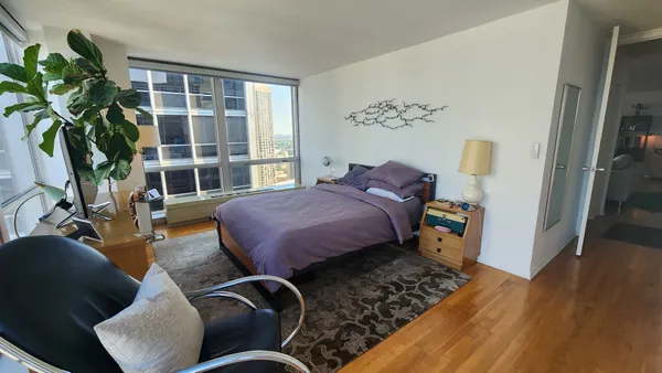 a spacious bedroom with a bed and wooden floor