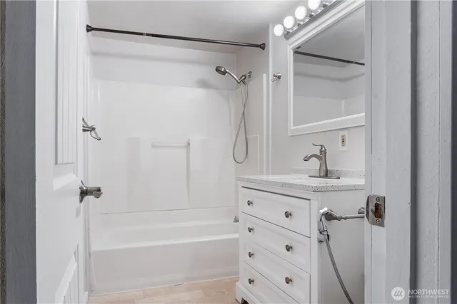 a bathroom with a tub sink vanity and mirror