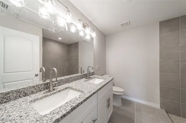 a bathroom with a granite countertop sink a toilet and a mirror