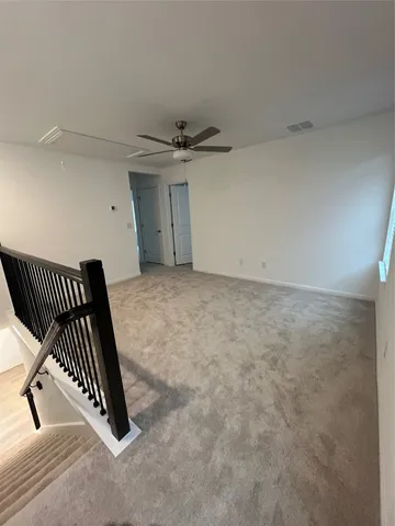 an empty room with a ceiling fan and rug