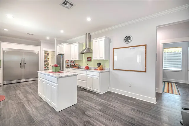 a kitchen with white cabinets and wooden floor