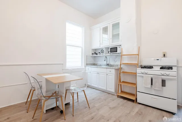 a kitchen with a stove a sink and white cabinets with wooden floors