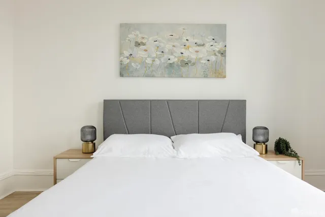 a bedroom with a bed and a lamp on dresser