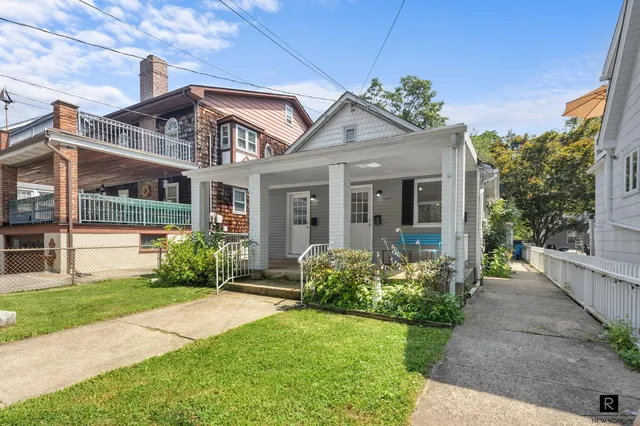 a front view of a house with a garden and tree