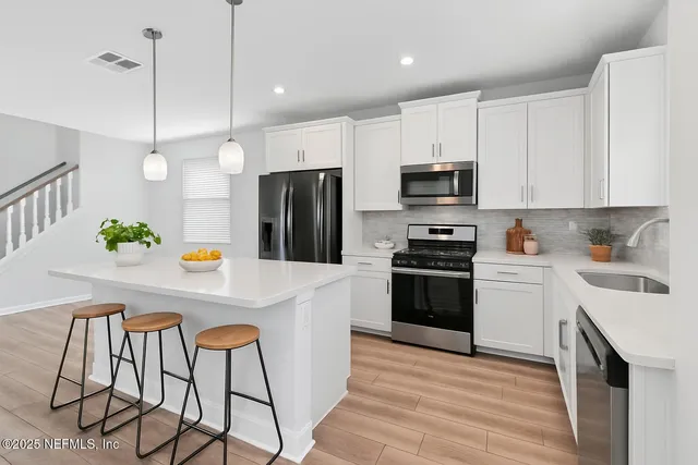 a kitchen with stainless steel appliances a stove a sink a refrigerator and a refrigerator