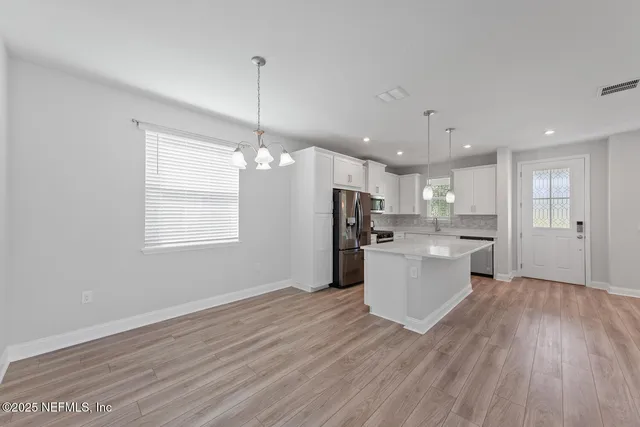 a large kitchen with a wooden floor and stainless steel appliances