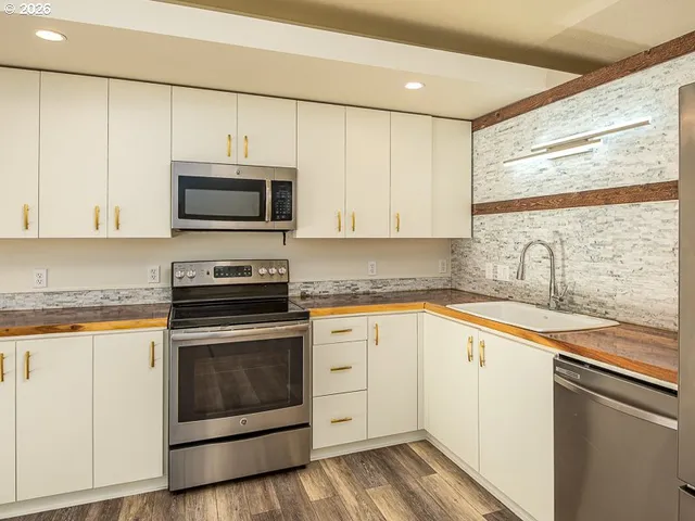 a kitchen with granite countertop white cabinets white stainless steel appliances and a sink