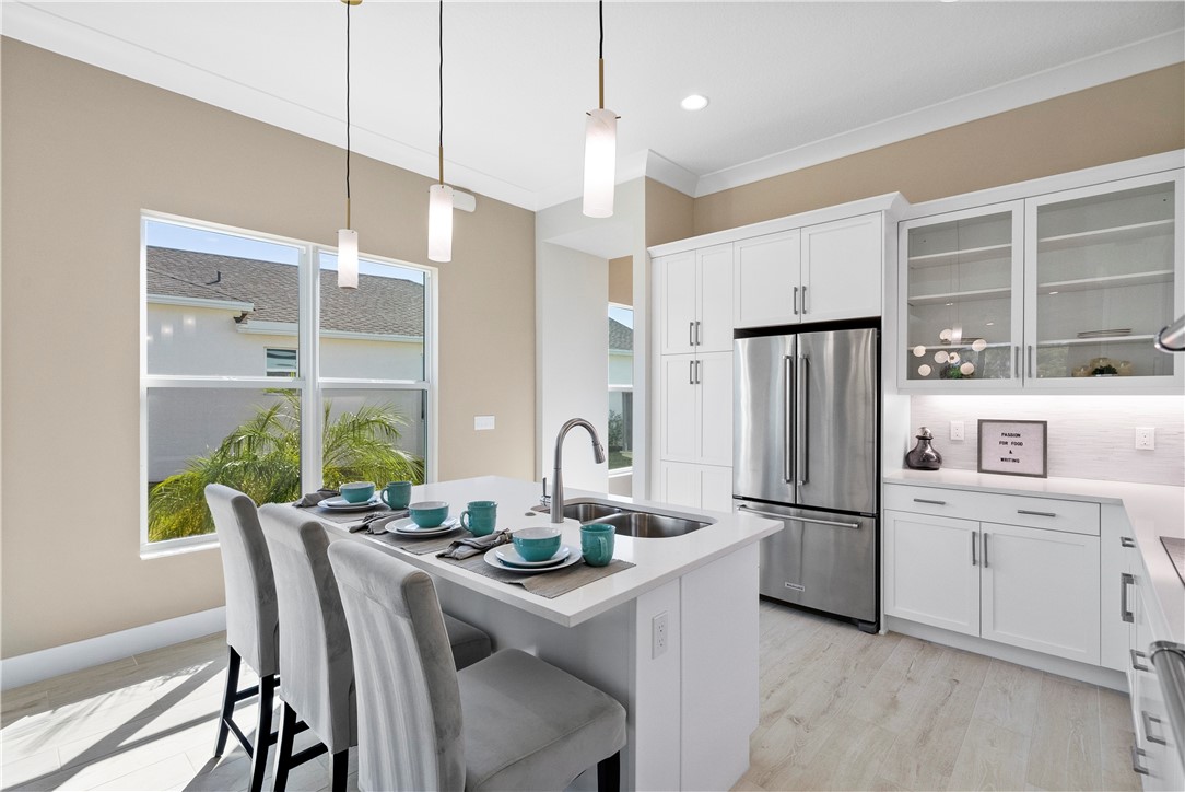 2148 Falls Manor Vero Beach, FL 32967 - Photo 11 of 25 a kitchen with a refrigerator a stove and a dining table with wooden floor