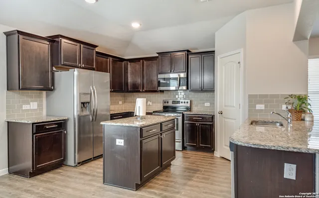 a kitchen with stainless steel appliances granite countertop a refrigerator stove a sink and dishwasher