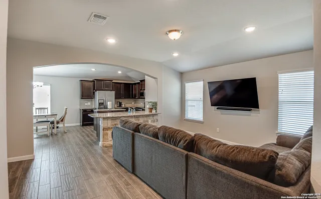 a living room with stainless steel appliances furniture and a flat screen tv