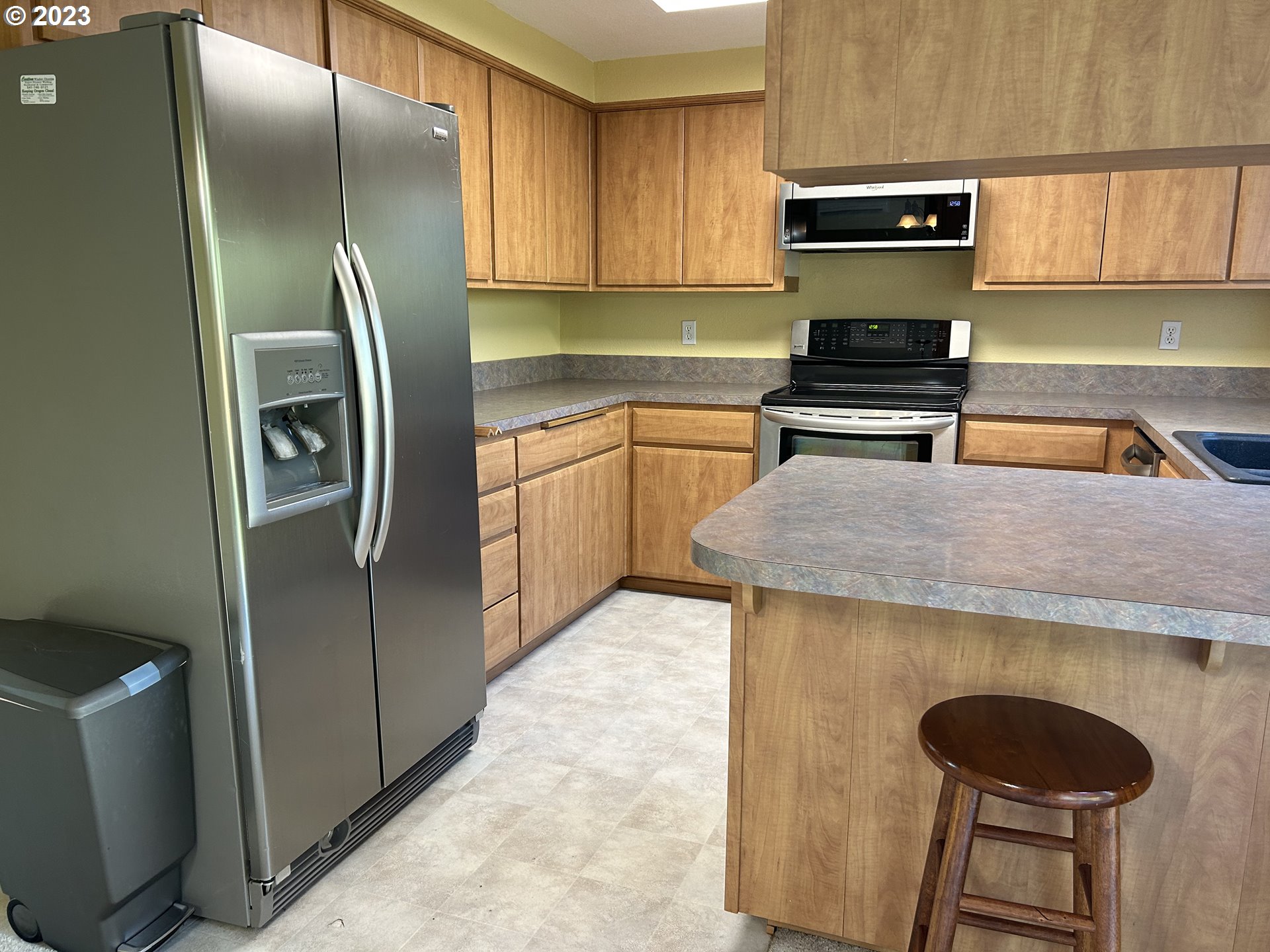 6558 Thurston Road Springfield, OR 97478 - Photo 11 of 26 a kitchen with stainless steel appliances granite countertop a refrigerator a stove and a sink with wooden cabinets